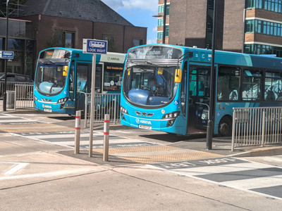 Two blue single-deck buses parked next to each other at the layover stands